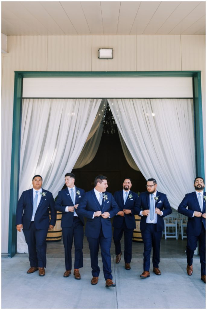groom and groomsmen in navy blue suits walking
