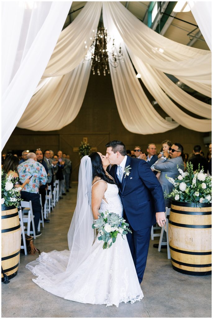 groom kissing bride at end of wedding aisle