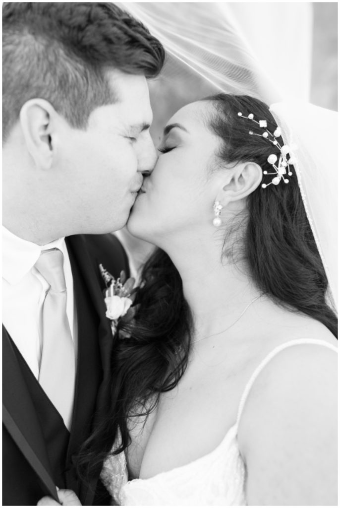 black and white close up image of bride and groom kissing