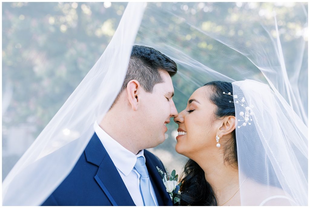bride and groom under wedding veil eyes closed noses touching by fresno wedding photographer megan helm photography