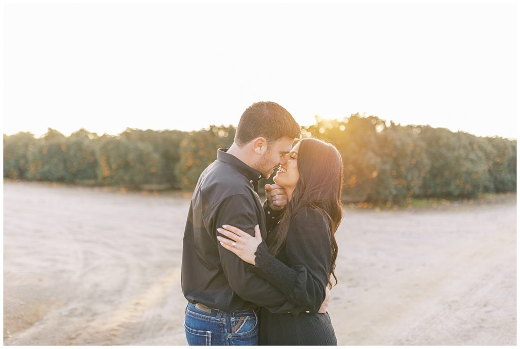 engaged couple about to kiss golden sun setting behind them