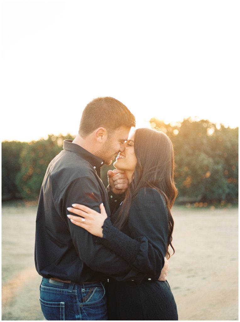 engaged couple about to kiss golden sun setting behind them dutton ranch inspired engagement photos