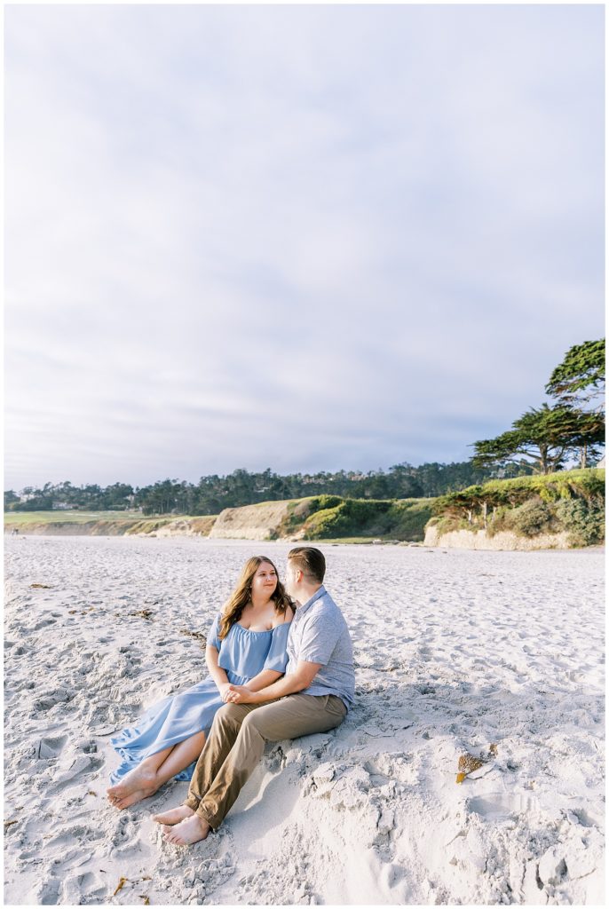 couple sitting on beach holding hands smiling