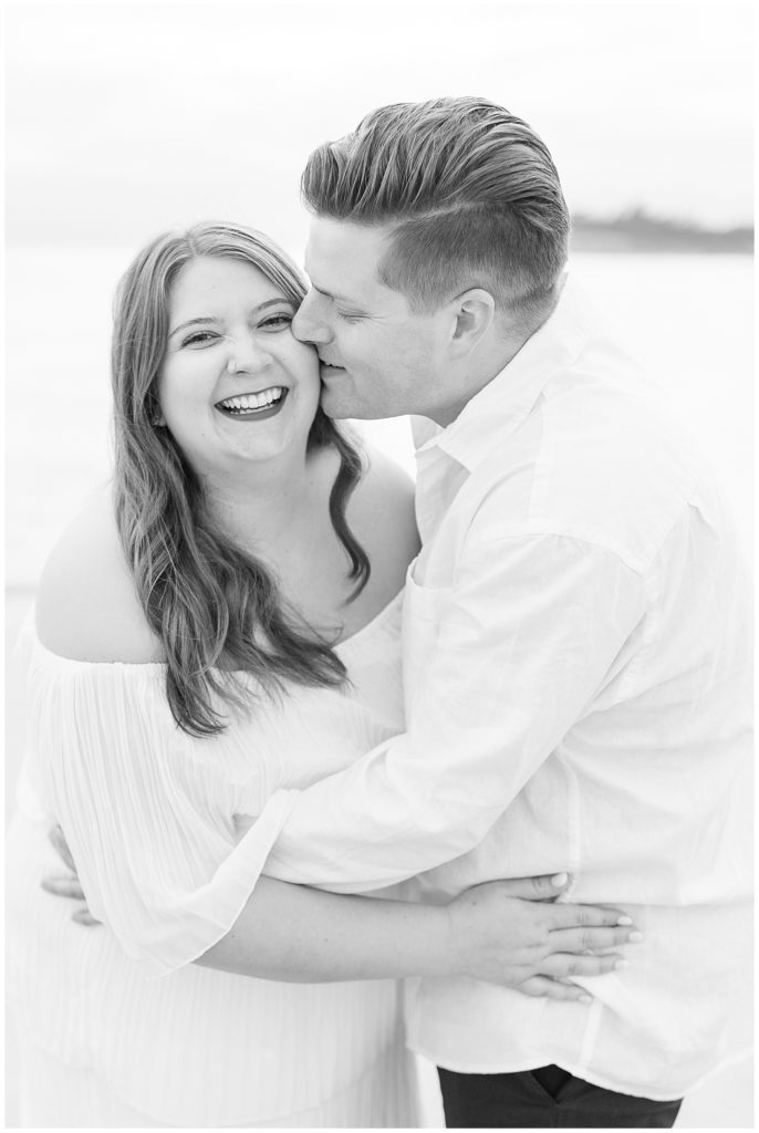 black and white image man kissing woman on cheek while woman smiles